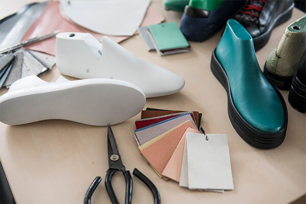 Der Werktisch eines Schuhmachers, inklusive einer Auswahl an Leder, Werkzeug und verschiedenen Vorlagen